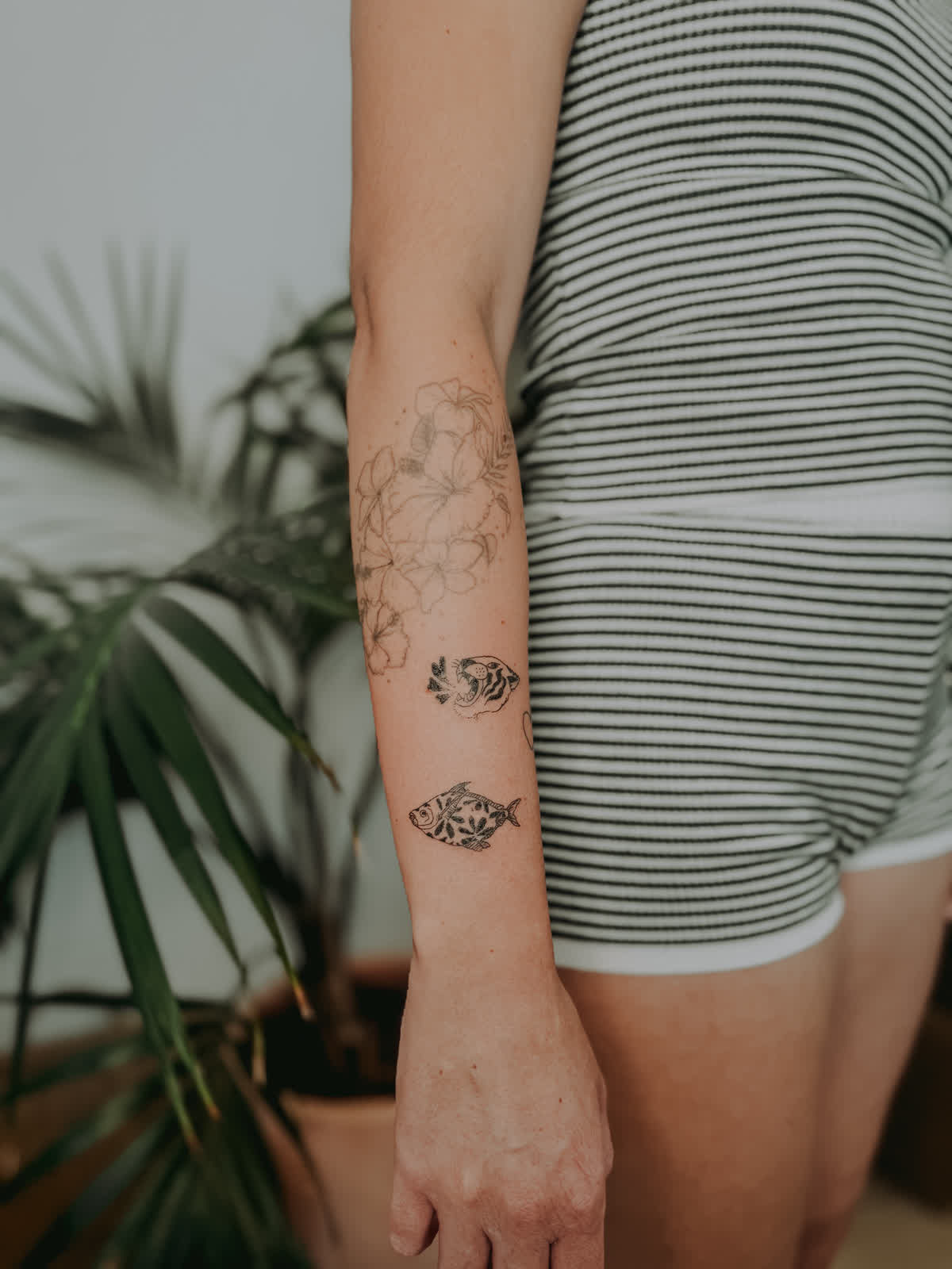 Hibiscus, tiger, and fish fine-line forearm piece